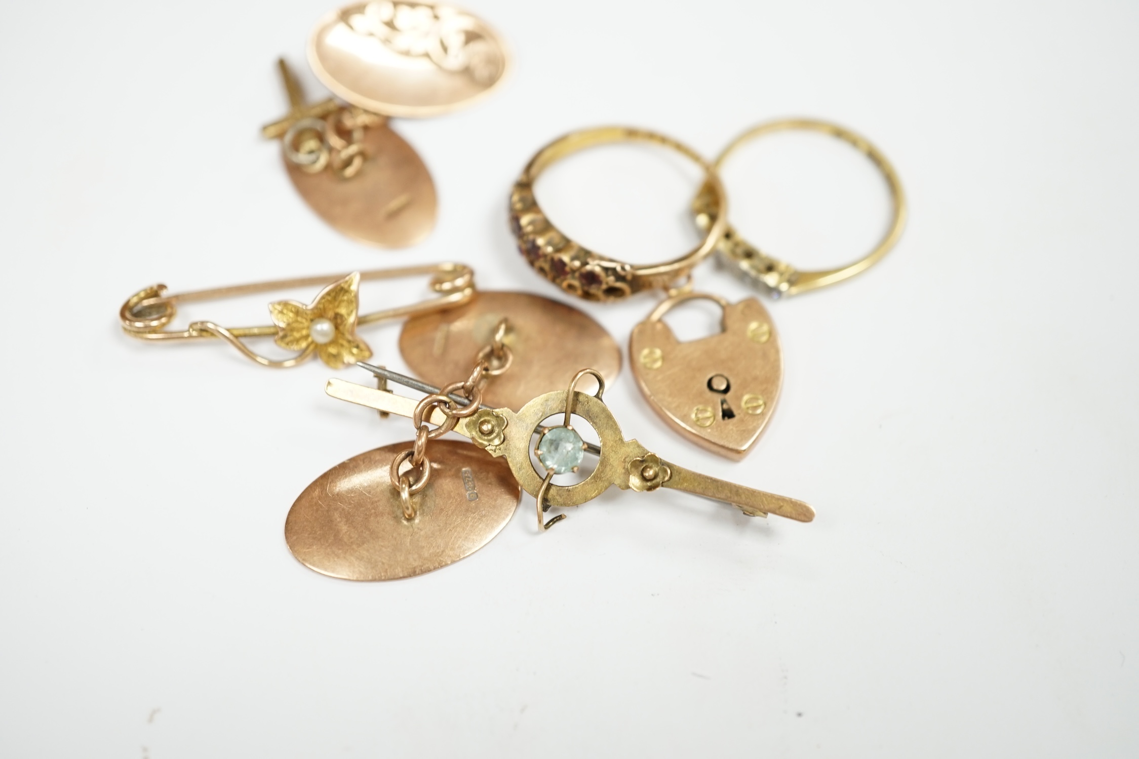 A pair of engraved 9ct gold oval cufflinks, two yellow metal bar brooches including 9ct, a 15ct gold and gem set ring (lacking stones), an 18ct and five stone diamond chip set ring and two 9ct charms. Condition - poor to